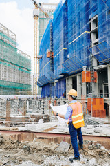 Civil engineer checking building blueprint when working on new project at construction site