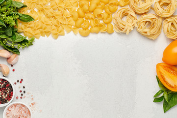 Different types of Italian pasta, fresh basil, orange tomatoes and garlic