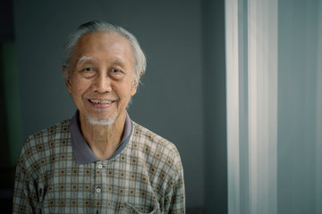 Smiling elderly man standing near the window