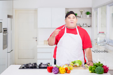 Young obese man enjoying tasty salad