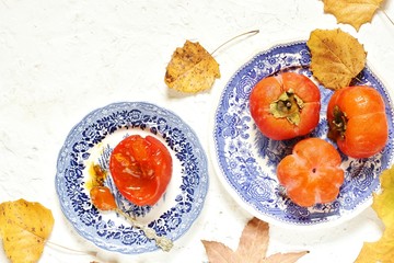 ripe juicy persimmons on a light background. You can eat with spoons like jelly. autumn still life flat. autumn leaves. top view, copy space