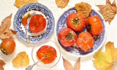 ripe juicy persimmons on a light background. You can eat with spoons like jelly. autumn still life flat. autumn leaves. top view, copy space