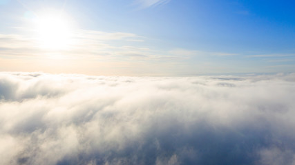 Aerial view White clouds in blue sky. Top view. View from drone. Aerial bird's eye view. Aerial top view cloudscape. Texture of clouds. View from above. Sunrise or sunset over clouds