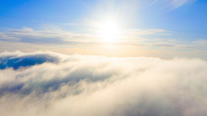 Obraz premium Aerial view White clouds in blue sky. Top view. View from drone. Aerial bird's eye view. Aerial top view cloudscape. Texture of clouds. View from above. Sunrise or sunset over clouds
