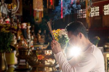 Faith and religious. .Man hands holding joss sticks praying and blessing in front of altar table at...