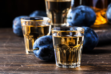 Slivovica - plum brandy or plum vodka, hard liquor, strong drink in glasses on old wooden table,...