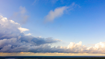 Obraz premium Aerial view White clouds in blue sky. Top view. View from drone. Aerial bird's eye view. Aerial top view cloudscape. Texture of clouds. View from above. Sunrise or sunset over clouds