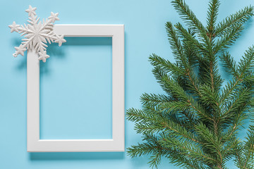 White frame with decoration snowflake and green spruce branch on blue background. Concept Merry christmas or Happy new year. Top view Flat lay Mockup Template for your design, card, invitation.