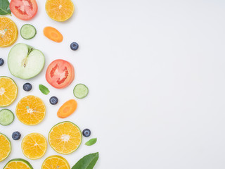 Fresh fruits and vegetables sliced on white background