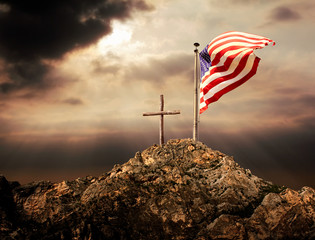 Conceptual image of waving American flag at tall pole and wooden cross over sunset sky