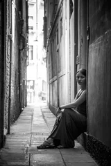 Fotobehang Outdoor photo of beautiful woman in elegant long dress, posing by the antic Venetian street. black and white. © simone_n