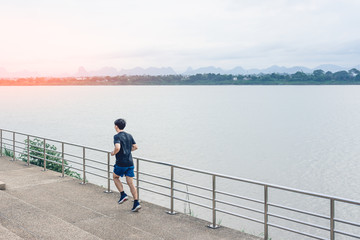 Young man running on the street with a view of the river in the morning.