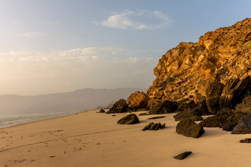 A beautiful scenic landscape of a beach with sand and rocks in the morning.