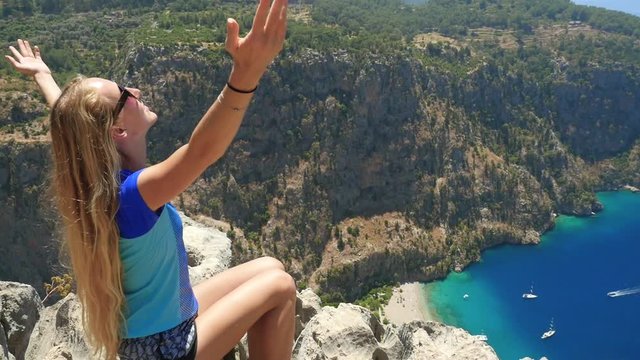 Young woman enjoying freedom and taking sun bath with beatiful viewn of Butterfly Valley on background in Turkey