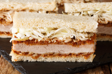 Tasty traditional japanese katsu sando sandwiches with tonkatsu sauce and cabbage close-up on a slate board on the table. horizontal