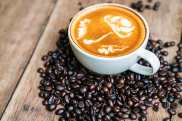 Latte art coffee in white cup with roast bean