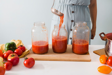 Woman pours tomato juice or fermented vegetable drink  in big jars on the table. Healthy eating and lifestyle concept.