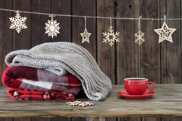 Fototapeta na wymiar stack of plaids, cup of tea and Christmas decorations on wooden background