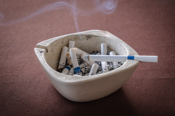 cigarette has been lit on the ashtray on red fabric texture background