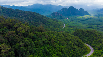 Naklejka na ściany i meble Winding road in mountain valley at sunset. Aerial view of asphalt road in thailand. Top view of roadway, mountains,Green forest, blue sky and sunlight