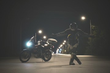 Naklejka na ściany i meble Biker is performing a curtsy on the night road.