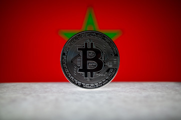 Physical silver version of Bitcoin (BTC) and Morocco Flag on the background. Conceptual image for investors in cryptocurrency and Blockchain Technology.
