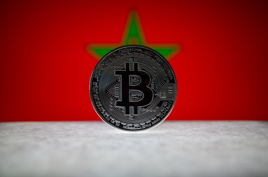 Physical silver version of Bitcoin (BTC) and Morocco Flag on the background. Conceptual image for investors in cryptocurrency and Blockchain Technology.