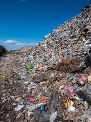 A large accumulation of various garbage, a landfill with a blue cloudy sky.