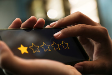 attractive hands giving one star rating on a smart phone