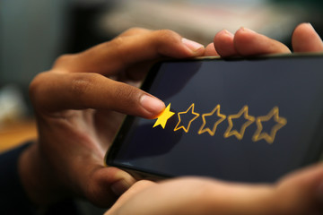 attractive hands giving one star rating on a smart phone