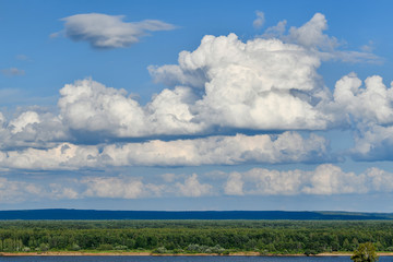 Beautiful cumulus clouds over the river and forest.