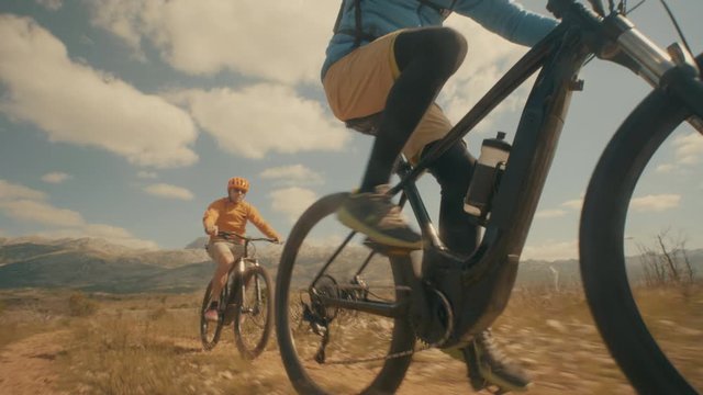 Low angle shot of two friends cycling through the desert