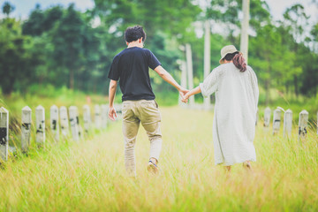 Lovers walking hand in hand grassland