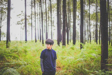 man walking in the deep pine forest with large backpack.