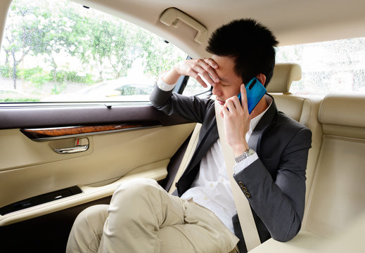 Stressed businessman calling on a mobile phone in the car