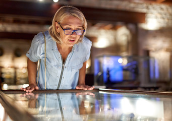 Woman visitor in the historical museum looking at art object.