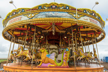 Fototapeta na wymiar Brightly coloured carousel on beach promenade.