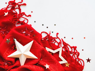 Bright red scarf with silver and golden stars confetti on white background. Folded warm accessory with copy space.