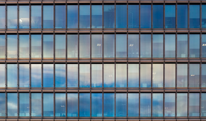 Detail of an office building with clouds reflecting in the glass facade