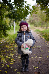 little girl with a toy sheep in the autumn park