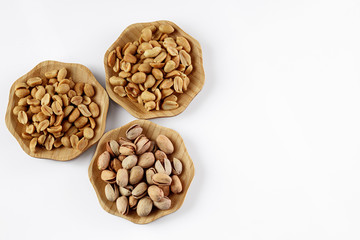 wood plates of salted peanuts and pistachios on white background. snack to beer