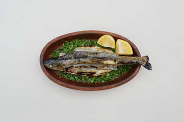 Georgian food. Grilled fish in a clay plate. Grilled Georgian mountain trout
