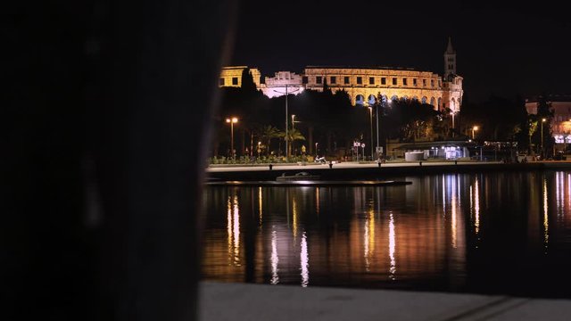 Beautiful time lapse reveal of Pula Arena, Croatia in the night with water reflection