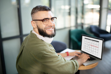 Bearded businessman smiling while working on laptop