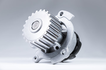 New metal automobile pump for cooling an engine water pump on a gray background with a gradient. The concept of new spare parts for the car engine