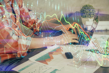 Double exposure of stock graph with businessman typing on computer in office on background. Concept of hard work.