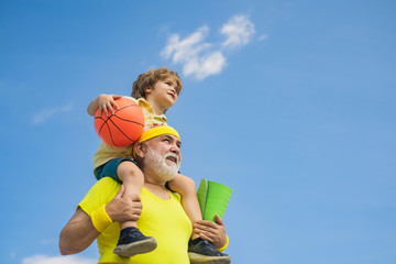 Preparing for morning workout in the park. Happy smiling boy on shoulder grandpa looking at camera....