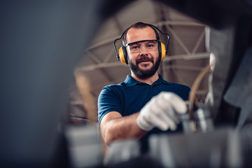 Factory worker operating band saw cutting machine