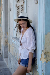 A casual fashion portrait of a young tourist woman in a summer outfit on the street