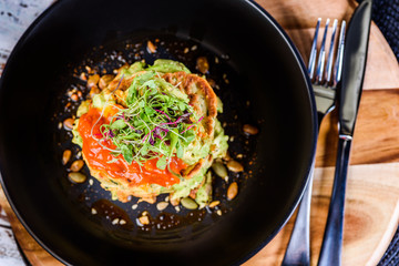 A dish of vegetable patties, Halloumi and Avocado, stacked up on a dark blue plate.